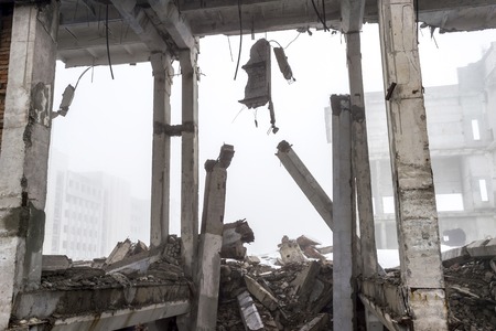 The remains of a large building destroyed in a foggy haze. Concrete piles of the building frame are prepared for demolition and disposal. Background.の写真素材