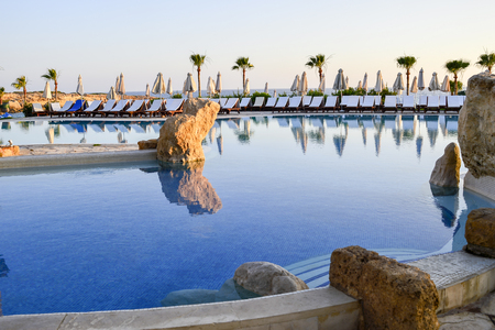 A number of sun loungers by the pool at the Coral Beach Hotel Resort Cyprus in June 2017 in Cyprus.のeditorial素材