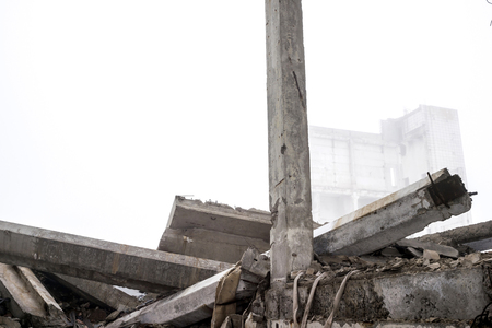 The destroyed big concrete building in a foggy haze. The remains of the frame of gray concrete piles and debris of the building structure. Background. Place to write the text.の写真素材