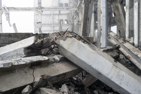 The destroyed big concrete building in a foggy haze. The frame of the building structure with huge piles lying in the foreground. Background.