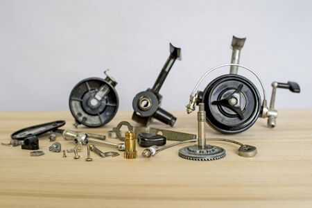 A fishing spinning reel as a whole and a second similar completely disassembled. Concept: parts of a whole. Preparation for the fishing season: prevention and application of lubricationの写真素材