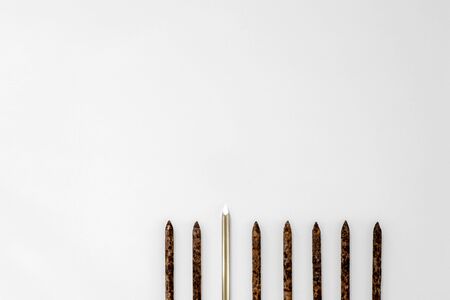 Metal shiny sharp nail stands out in a row of old rusty nails on a light background.の写真素材
