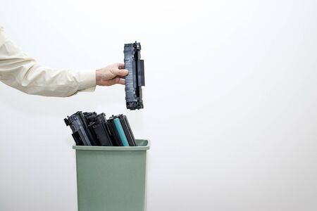 Male hand office worker puts in a bucket of spent cartridges. Background.