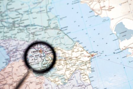 Georgia with the capital of Tbilisi close-up through a magnifying glass on the background of a blurred geographical map.の写真素材
