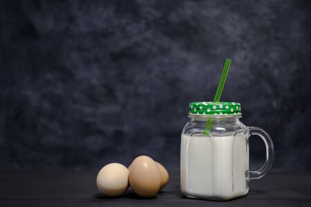 Protein white cocktail in a mug and chicken eggs on a dark background. Background. Concept of sports nutrition and protein diet.の写真素材