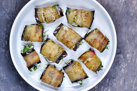 Rolls of fried eggplant close-up on a white plate on a vintage backgroundの写真素材