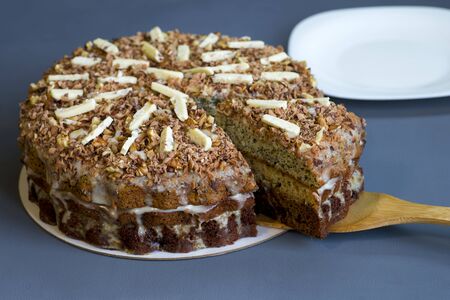 Chocolate cake with a separate piece on a bamboo spatula on a dark background with a white plate.の写真素材