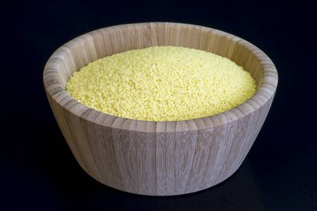 Dry couscous close-up in a bamboo deep bowl on a dark background. Concept of Oriental cuisine dishes.の写真素材
