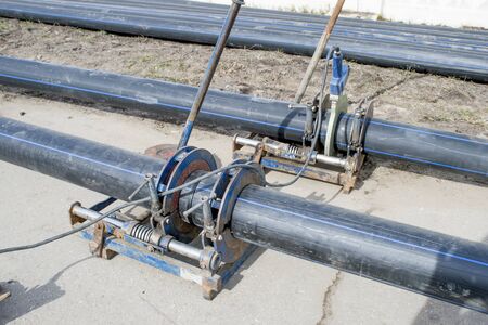 Laying of municipal Sewerage pipeline. Docking and sealing with an industrial soldering iron of polymer black pipes with marking.の写真素材
