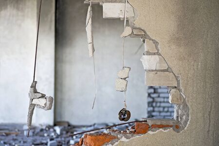 The destroyed brick wall of the building with the remains of communications in the form of wiring....