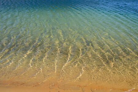 Clear blue water with light waves and beautiful sun glare. Natural background.の写真素材