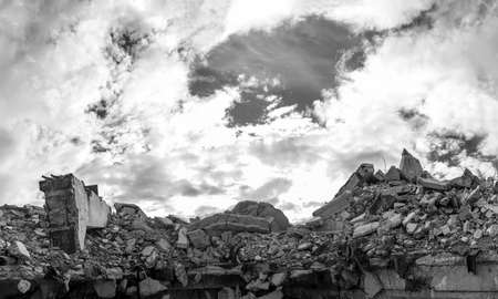 A pile of concrete gray debris of a destroyed building with a huge beam in the foreground against the background of a textured sky with clouds.の写真素材