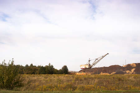 A large walking excavator forms dumps of rock delivered by freight train from a mining quarry. background.の写真素材