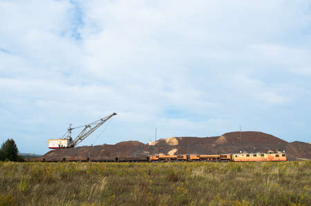 A large walking excavator forms dumps of rock delivered by freight train from a mining quarry. background.の写真素材