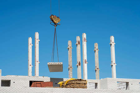 Supply of concrete slabs with a crane during the construction of a brick house. No body.