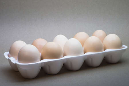 Chicken eggs close-up in a white polymer tray on a cardboard background.の写真素材