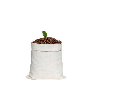 Coffee beans with a green leaf in a bag made of light linen fabric isolated on a white background.の写真素材