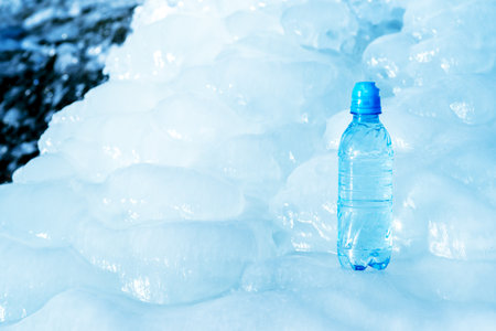 Blue plastic bottle on ice against the background of the glacier meltwater flow. Background.の写真素材