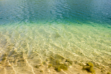 Clear clear water of the lake with a turquoise hue on a sandy beach. The natural backgroundの写真素材