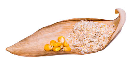 Corn bran with yellow corn kernels on a dry brown corn leaf cut on an isolated white background.の写真素材