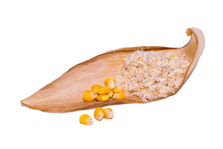 Corn bran with yellow corn kernels on a dry brown corn leaf cut on an isolated white background.の写真素材