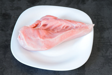 Raw chicken breast fillet close-up on a white plate on a vintage background. The concept of healthy eating.の写真素材