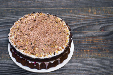 Chocolate cake decorated with grated chocolate with walnuts with fruit filling on a gray wooden vintage background. background. The concept of making a cake.の写真素材