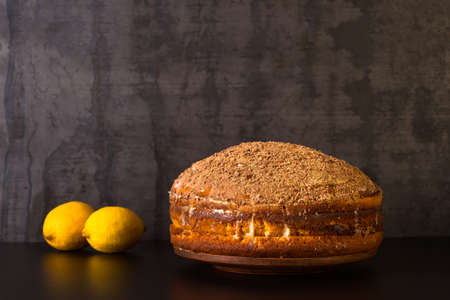 Lemon cake sprinkled with grated chocolate with lemons on a dark vintage background. The concept of making dessertの写真素材