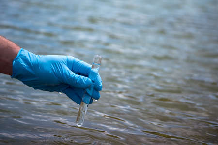 water sample. A man's hand in a blue glove takes a sample water into a test tube. The concept of analysis of water purity, environmental pollution. Water testing for infections. background, copy spaceの写真素材