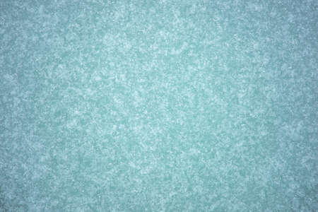 Ice with a greenish-gray tint is textured with white frost with a slight natural illumination and a curly pattern of ice. Backgroundの写真素材