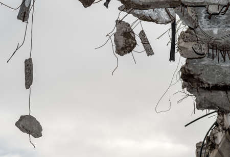Concrete fragments on metal fittings with the remains of a building in close-up against a gray sky. Backgroundの写真素材