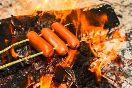 Beef sausages are fried on an open fire. background. The concept is a camp kitchen.の写真素材
