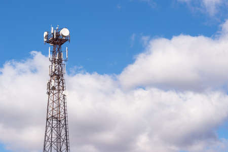A high-rise telecommunications tower made of metal structure against a blue sky with gray clouds. background.の写真素材