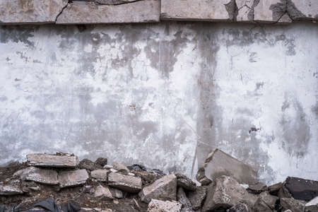 Concrete wall with remnants of white plaster framed by construction debris. background.の写真素材