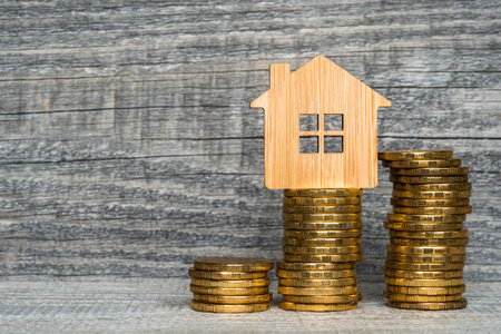 Bamboo house with yellow coins in the form of a close-up graph on a wooden gray background. The concept of the growth of utility payments of the populationの写真素材