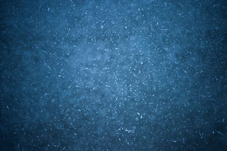 An icy dark background with white patches of frost and frozen round bubblesの写真素材