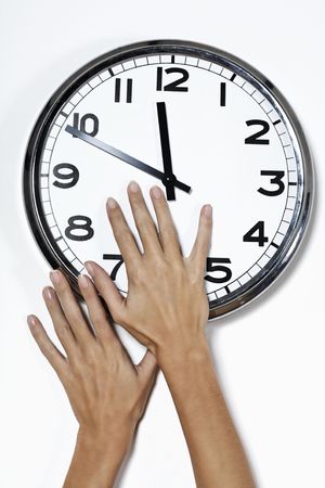 hands trying to stop the advance of the time by grabbing needle of a clockの写真素材