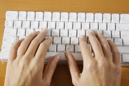 hand typing on a wireless white keyboard computer posed on atableの写真素材
