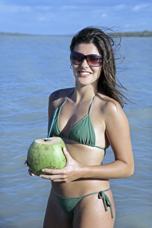 beautiful smiling bikini dressed young brazilian  woman drinking and holding fresh coconut juice in the tatajuba lagoon in jericoacoara ceara state near fortalezaの写真素材