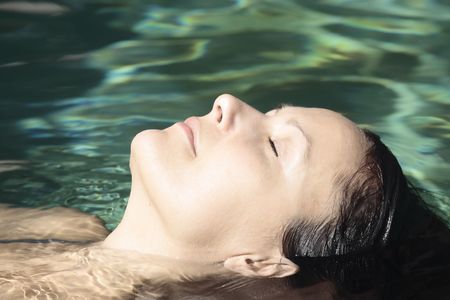 beautiful brunette caucasian relaxing in a swimming poolの写真素材