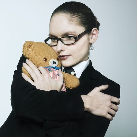 studio shot portrait of a beautiful young woman in a costume suit holding a teddy beaの写真素材