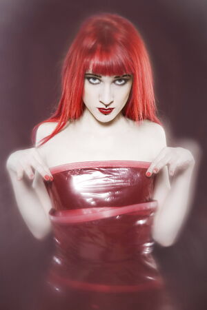 Funny & sexy expressive redhead girl wearing a palstic coat and dress on isolated backgrounの写真素材