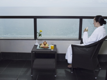 beautiful calm and serene woman in palace hotel room at the balcony facing the seaの写真素材
