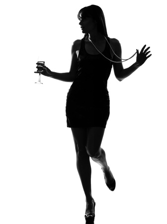 stylish silhouette caucasian beautiful woman partying drinking champagne flute glass cocktail full length on studio isolated white backgroundの写真素材