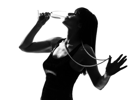 stylish silhouette caucasian beautiful woman partying drinking champagne flute glass cocktail full length on studio isolated white backgroundの写真素材