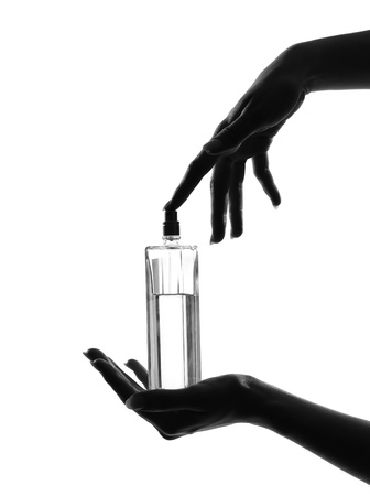 detail close-up silhouette in shadow of a  woman hands holding perfume in studio on white background isolatedの写真素材