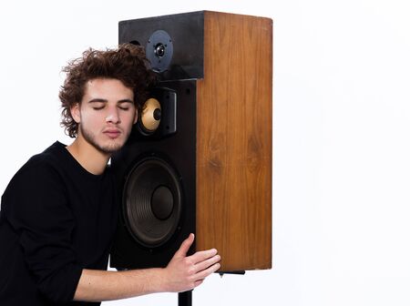 studio portrait of a one caucasian young man listening to music lover with speakerphones isolated on white backgroundの写真素材