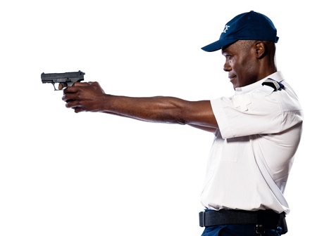 Side view of an afro American police officer aiming gun in studio on white isolated backgroundの写真素材