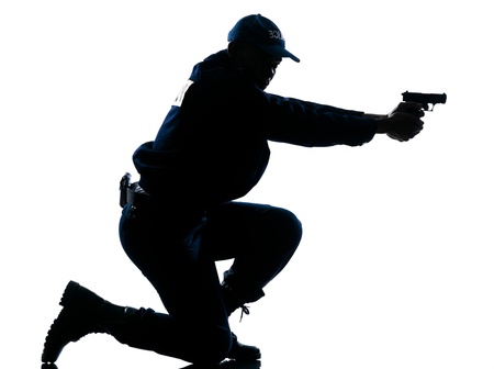 Side view of a silhouetted Afro American police officer aiming gun isolated on white backgroundの写真素材