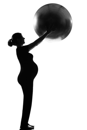 beautiful caucasian pregnant woman with fitness ball in full length silhouette on studio isolated white backgroundの写真素材